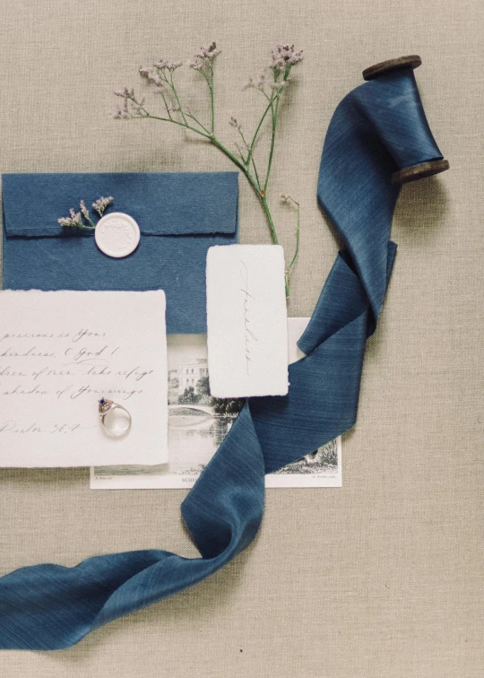 a couple of cards sitting on top of a table, inspired by Jean Hey, trending on unsplash, renaissance, satin ribbons, soft blue texture, wedding, product introduction photo