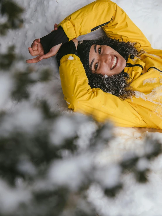 a woman in a yellow jacket laying in the snow, pexels contest winner, smiling spartan, high quality product image”, avatar image, body shot