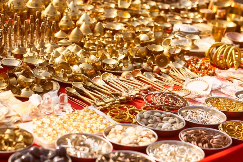 a table filled with lots of gold and silver items, gold and red metal, street vendors, shiny brass, shells