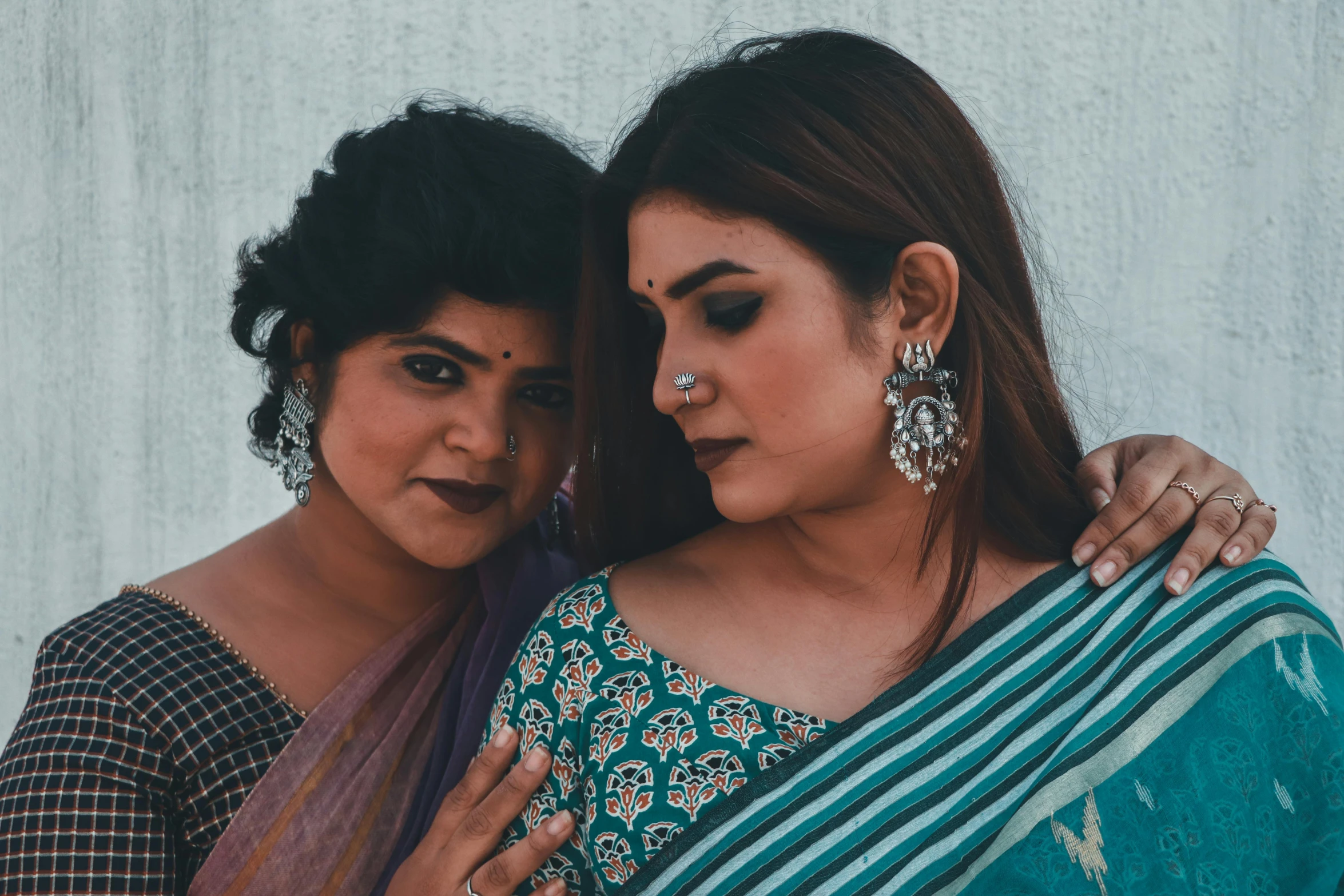 a couple of women standing next to each other, trending on pexels, hurufiyya, huge earrings and queer make up, sari, blueish, icon