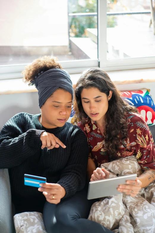 two women sitting on a couch looking at a tablet, trending on pexels, renaissance, people shopping, square, aida muluneh, lesbian