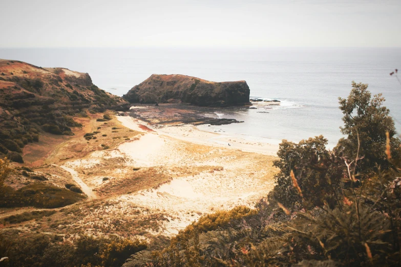 a view of a beach from the top of a hill, unsplash contest winner, australian tonalism, caramel. rugged, island with cave, grainy vintage, looking partly to the left