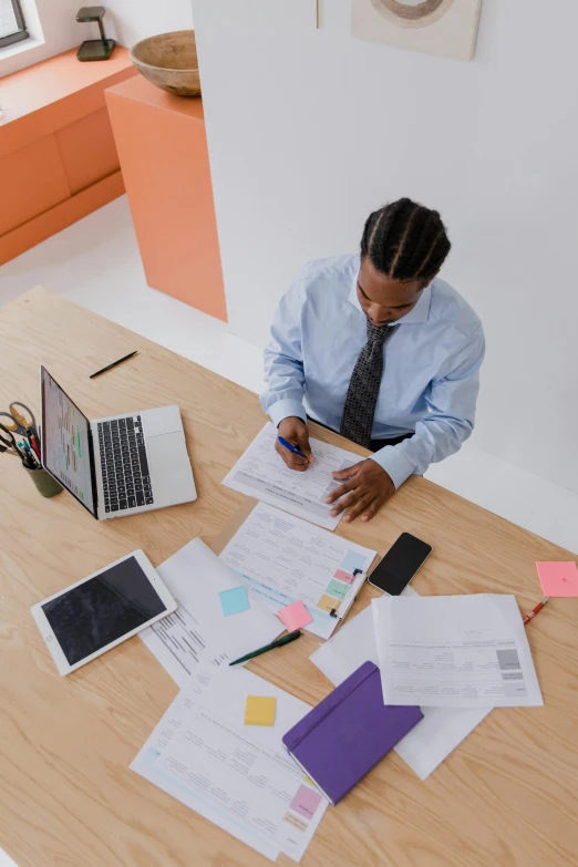 a man sitting at a table with papers and laptops, trending on pexels, standing on a desk, topknot, varying ethnicities, thumbnail