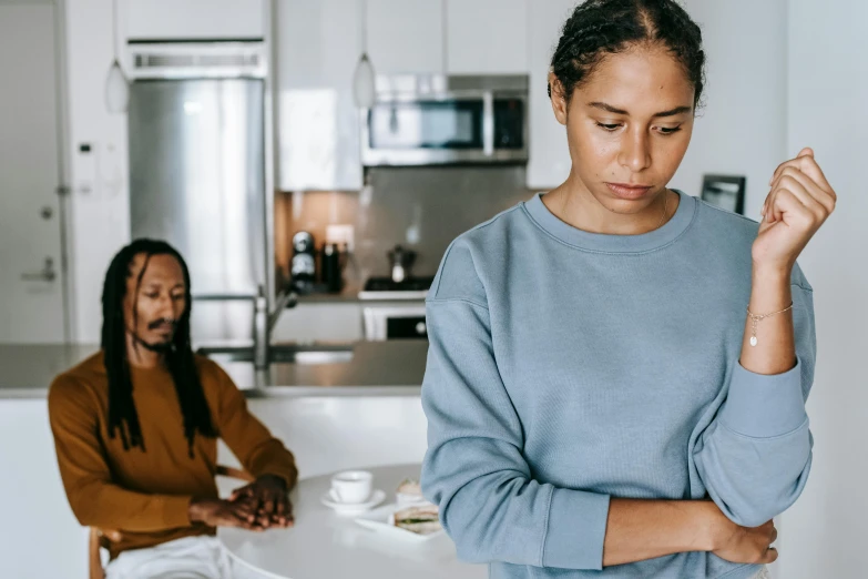 a woman standing next to a man in a kitchen, trending on pexels, emotional pain, background image, woman holding another woman, photo of a black woman