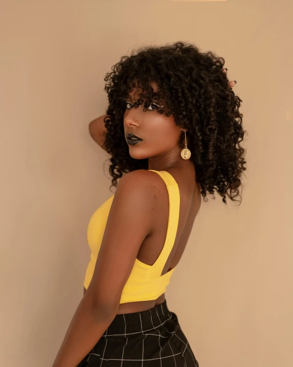 a woman in a yellow top and black pants, inspired by Theo Constanté, trending on pexels, with textured hair and skin, 🍸🍋, dark natural glow, iridescent skin