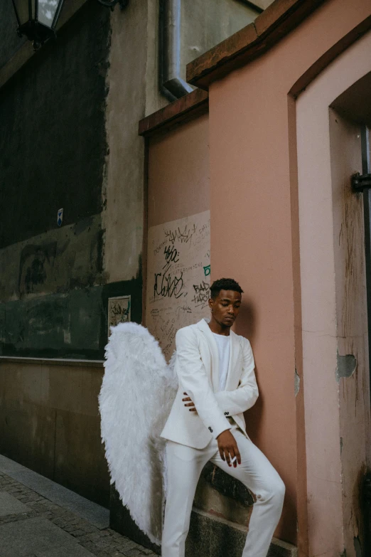 a man in a white suit leaning against a wall, pexels contest winner, renaissance, girl with angel wings, tyler the creator, in barcelona, non binary model
