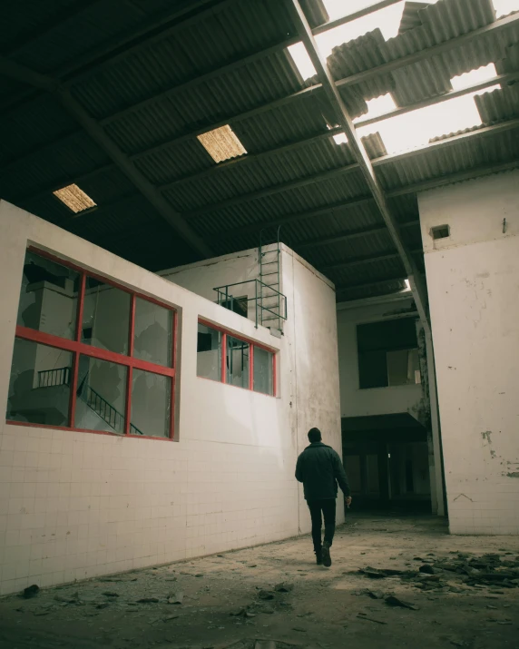 a man walking through a building under construction, an album cover, inspired by Elsa Bleda, pexels contest winner, in a warehouse, looking sad, white building, still from a music video