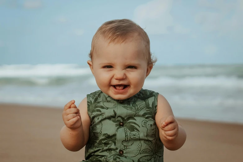 a baby standing on top of a sandy beach, smiling with confidence, patterned, palm body, manly