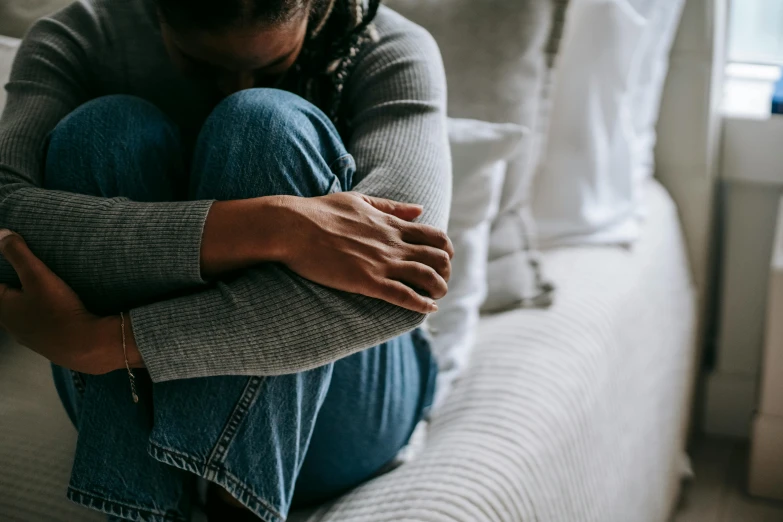 a woman sitting on a couch with her hands on her knees, trending on pexels, hugging, grieving, wearing jeans, instagram photo