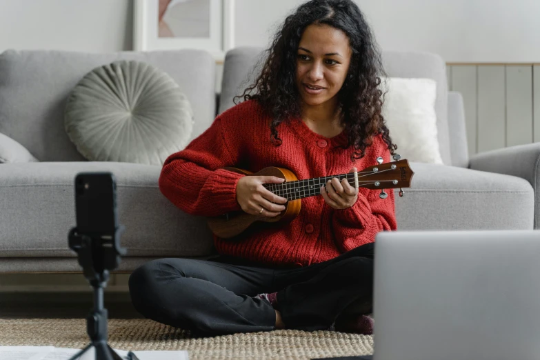 a woman sitting on the floor playing a guitar, pexels contest winner, hurufiyya, wearing a red turtleneck sweater, avatar image, home video footage, ukulele