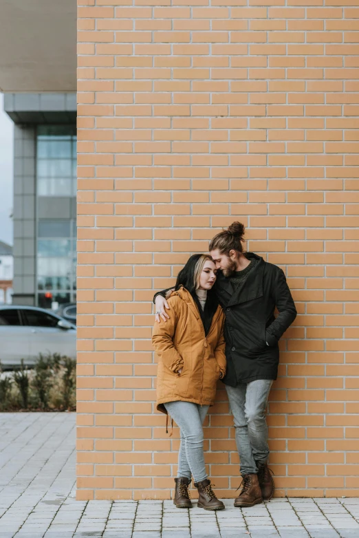 a man and woman leaning against a brick wall, a picture, by Jan Tengnagel, pexels contest winner, wearing jacket, beautiful girlfriend, solid background, outside in parking lot