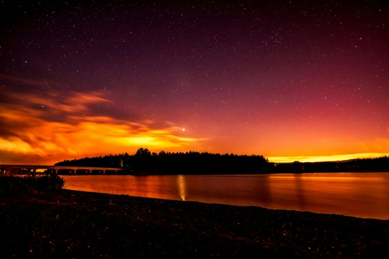 a large body of water under a purple sky, by Jesper Knudsen, pexels contest winner, dark orange night sky, forest fires in the distance, visible planets in the sky, washington state