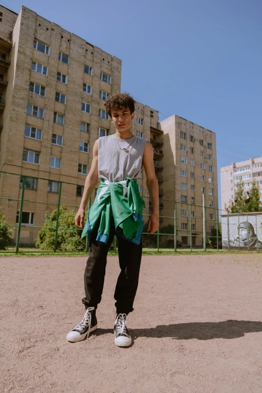 a young man standing on a skateboard in front of a building, an album cover, by Attila Meszlenyi, unsplash, russian clothes, non binary model, wearing tank top, in an arena