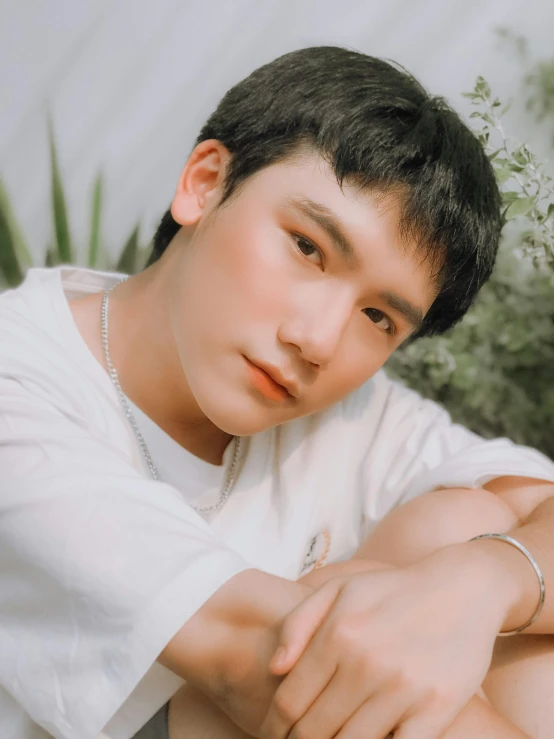 a young man sitting next to a potted plant, an album cover, inspired by Bian Shoumin, trending on pexels, photorealism, thick jawline, lovingly looking at camera, glowing white face, bao pnan