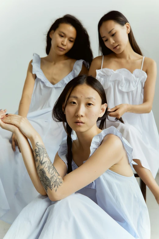 a group of women sitting next to each other, inspired by Kim Tschang Yeul, trending on pexels, gutai group, wearing a nightgown, pale blue, frill, fashion model features