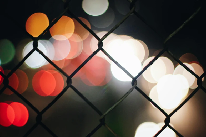 a close up of a chain link fence with lights in the background, inspired by Elsa Bleda, unsplash, multicolored, instagram picture, midnight city lights, instagram post