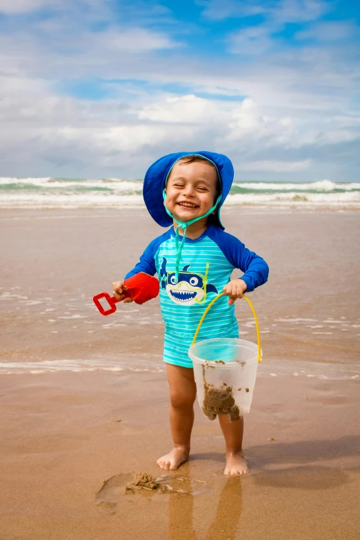 a little boy standing on top of a sandy beach, at a beach, profile image