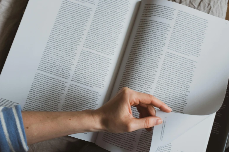 a person reading a book on a bed, private press, white paper, background image, sustainable materials, finding words