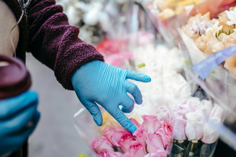 a person in a blue glove is picking flowers, by Meredith Dillman, pexels, stood in a supermarket, made of lab tissue, vendors, sydney hanson