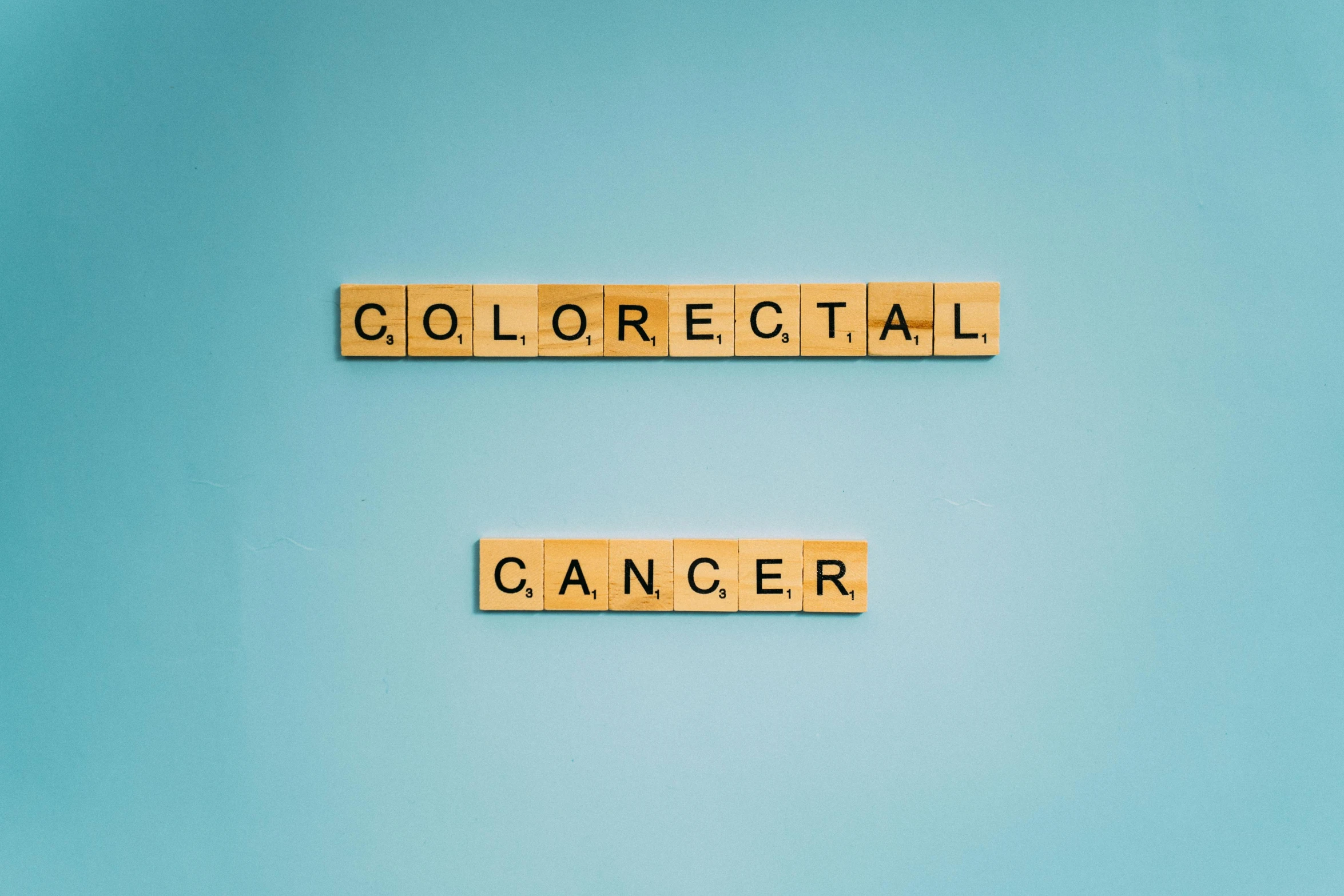 scrabbles spelling the word colorectal cancer on a blue background, an album cover, colour corrected, on a dark background, collosal mech, 4l