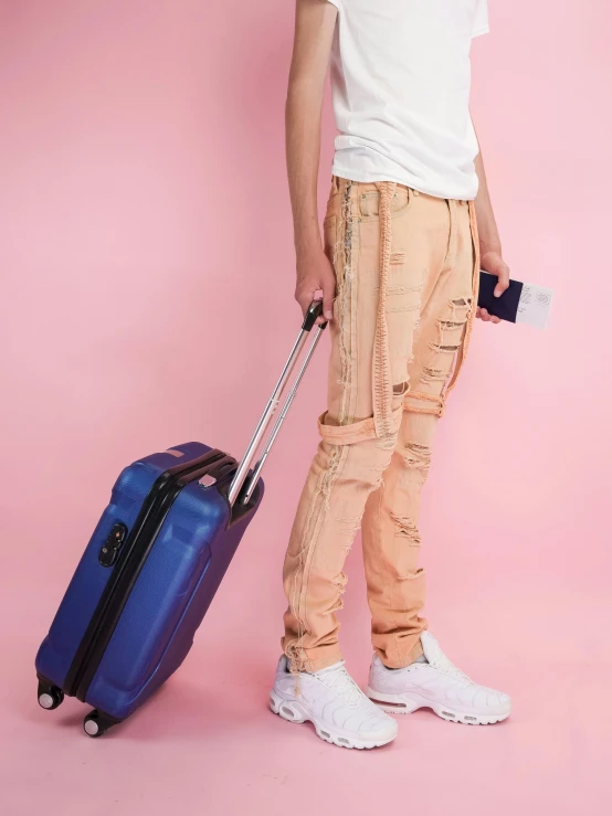 a young man standing next to a blue suitcase, by Nina Hamnett, happening, toned orange and pastel pink, ripped jeans, trending on r/techwearclothing, profile image