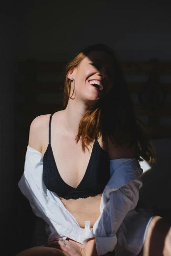 a woman sitting on top of a bed next to a window, pexels contest winner, earing a shirt laughing, in a black betch bra, a redheaded young woman, large)}]