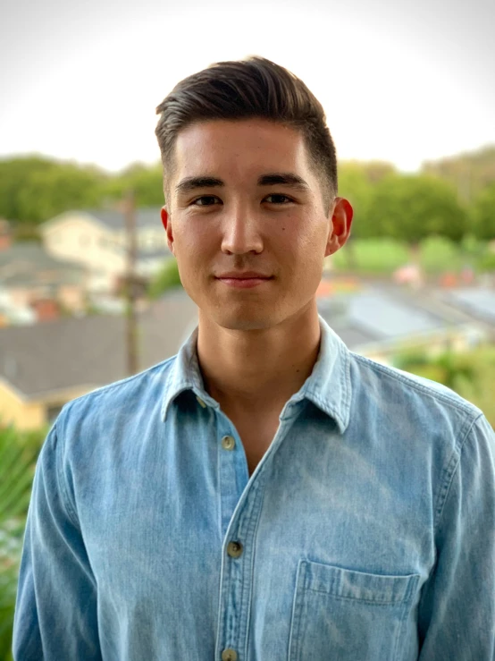 a man in a blue shirt posing for a picture, reuben wu, lean man with light tan skin, lgbtq, centered face shot