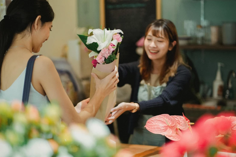 a woman handing a bouquet of flowers to another woman, pexels contest winner, japanese collection product, at the counter, front and center, welcoming grin