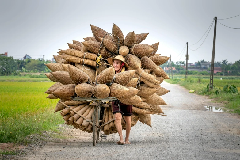 a person riding a bike down a dirt road, wearing huge straw hat, big pods, bao phan, stacked image