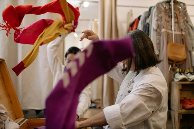 a woman is working in a clothing store, inspired by Josefina Tanganelli Plana, pexels contest winner, process art, waving robe movement, woman holding another woman, studio kyoto, thumbnail