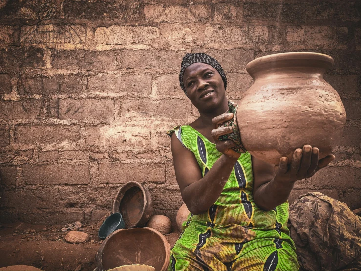 a woman in a green dress holding a clay pot, by Ingrida Kadaka, pexels contest winner, african man, avatar image, handcrafted, highly textured