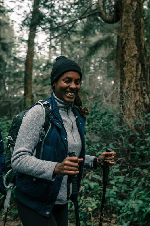 a woman smiles while hiking through the woods, a portrait, pexels contest winner, black female, pacific northwest coast, panel of black, [ cinematic