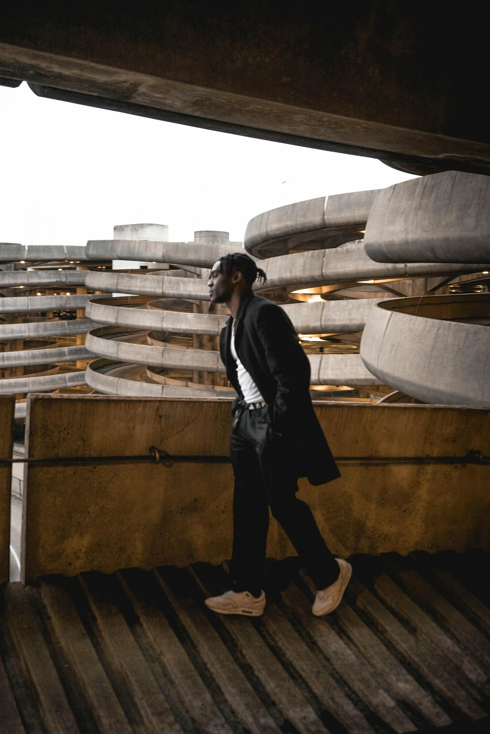 a man standing on top of a wooden floor, by Maxwell Bates, pexels contest winner, brutalism, young thug, black. airports, profile pic, in an underground parking garage