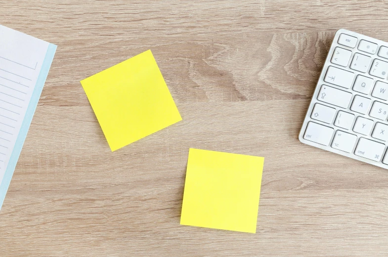 a notepad sitting on top of a wooden desk next to a keyboard, yellow, thumbnail, square, squares