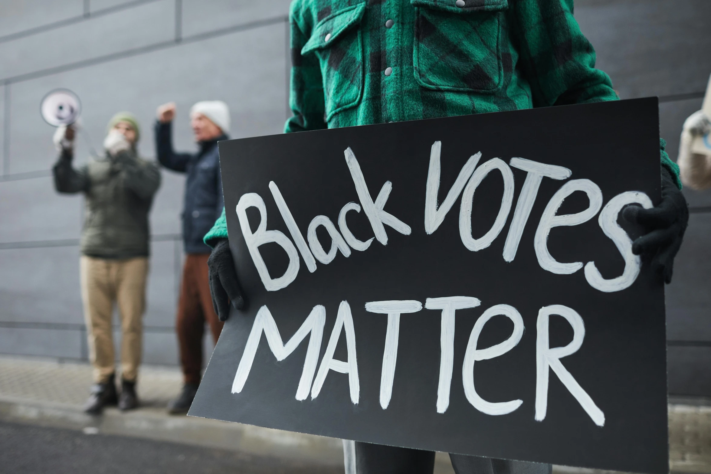 a person holding a sign that says black votes matter, a black and white photo, shutterstock, trending on, standing, bl, contain