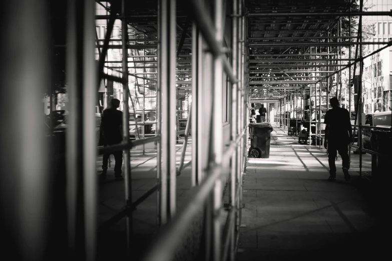 a black and white photo of people walking down a sidewalk, unsplash, constructivism, in a factory, scaffolding, shot on iphone 6, in a square