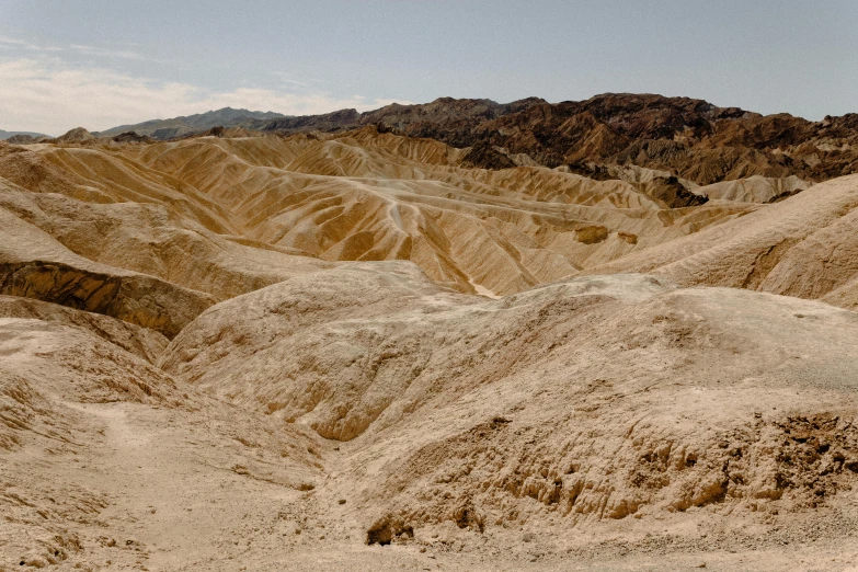 a man riding a skateboard on top of a sandy hill, by Julia Pishtar, unsplash contest winner, shiny layered geological strata, death valley, ancient ochre palette, 1940s photo