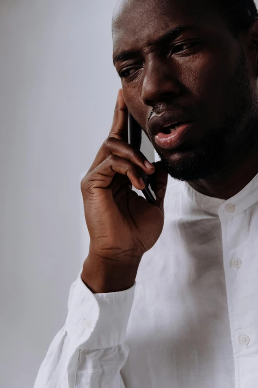 a man in a white shirt talking on a cell phone, trending on pexels, hyperrealism, ( ( dark skin ) ), brown, upsetting, kano)