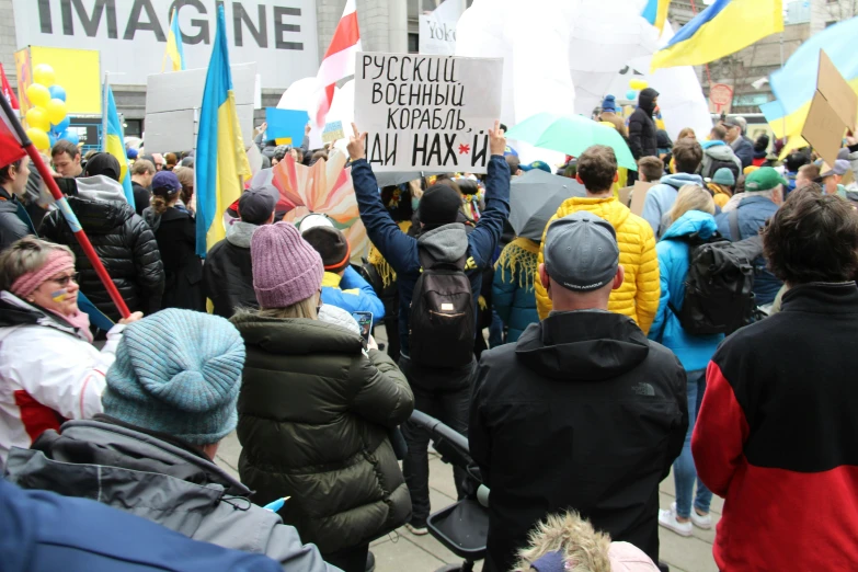 a large group of people holding flags and signs, a photo, by Maksimilijan Vanka, pexels, renaissance, yellow and blue and cyan, square, dasha taran, with his back turned