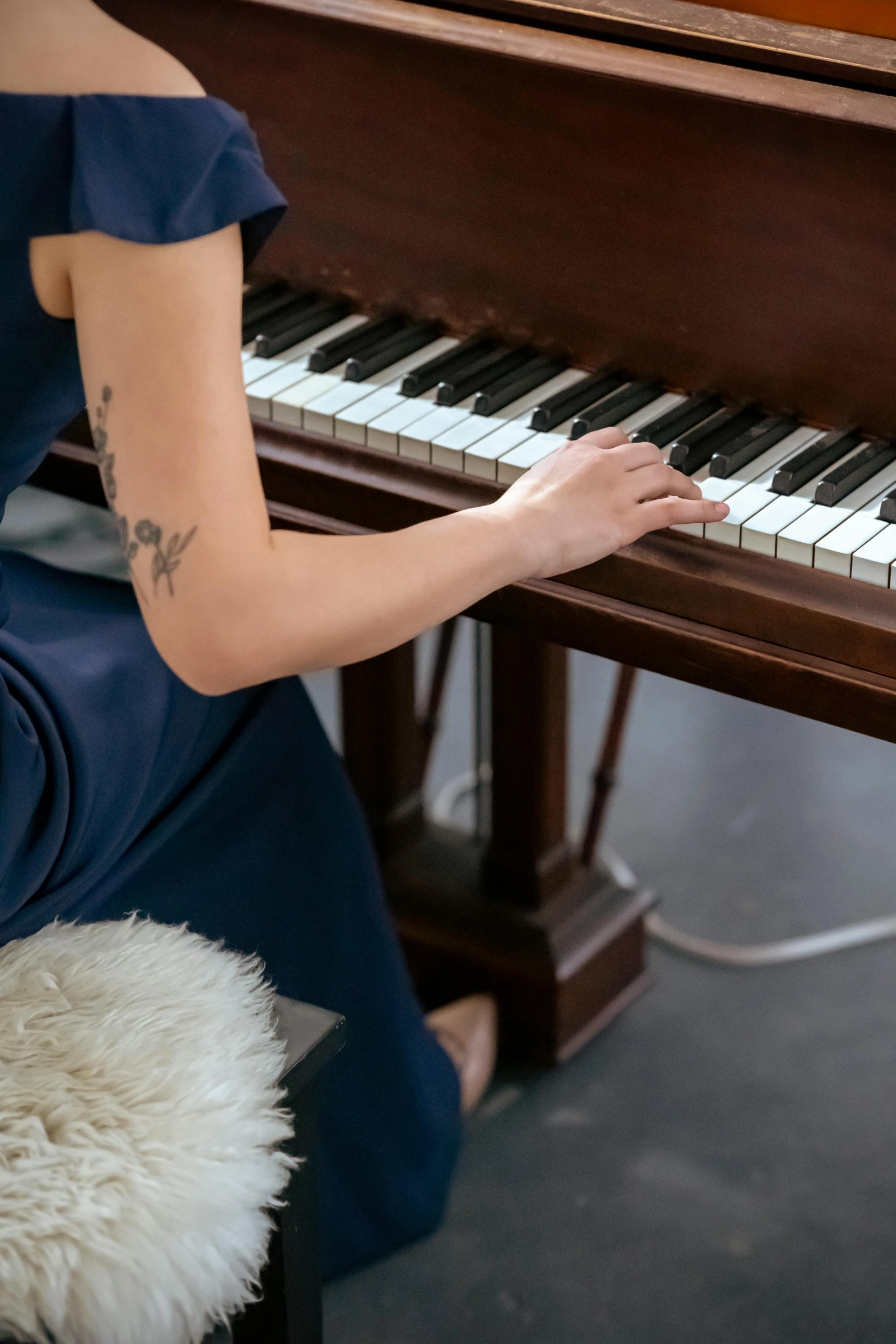 a woman in a blue dress playing a piano, trending on pexels, tattooed, sitting on a mocha-colored table, low detail, long