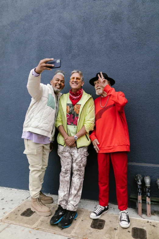 a group of people standing next to each other on a sidewalk, a photo, unsplash, black arts movement, older male, wearing red clothes, hypermaximalist, taking selfies