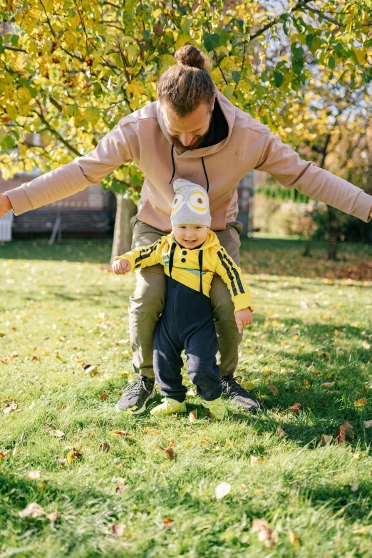 a woman and a child playing with a frisbee, a picture, by Niko Henrichon, pexels contest winner, wearing a yellow hoodie, walking on grass, father with child, wearing a track suit