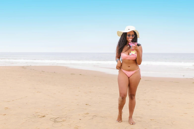 a woman standing on top of a sandy beach, by Lily Delissa Joseph, pexels contest winner, light pink bikini, ( brown skin ), full body frontal view, she is wearing a hat