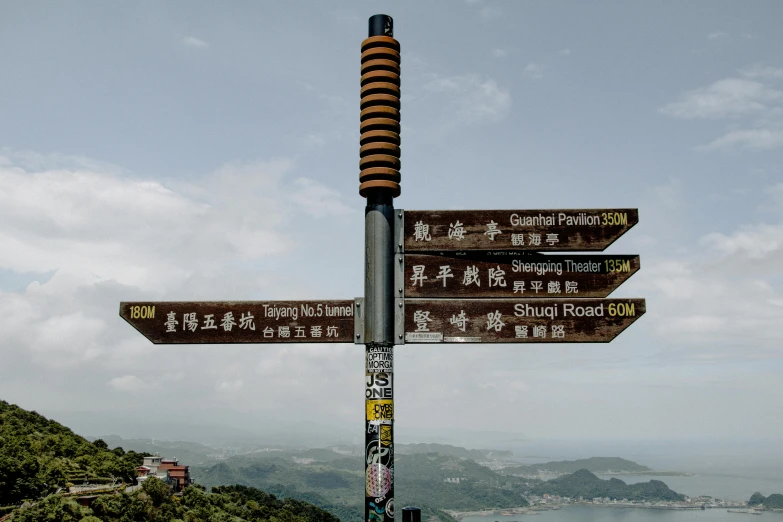 a pole that has a bunch of signs on it, a picture, by Daniel Lieske, pexels, like jiufen, on the top of a mountain, avatar image