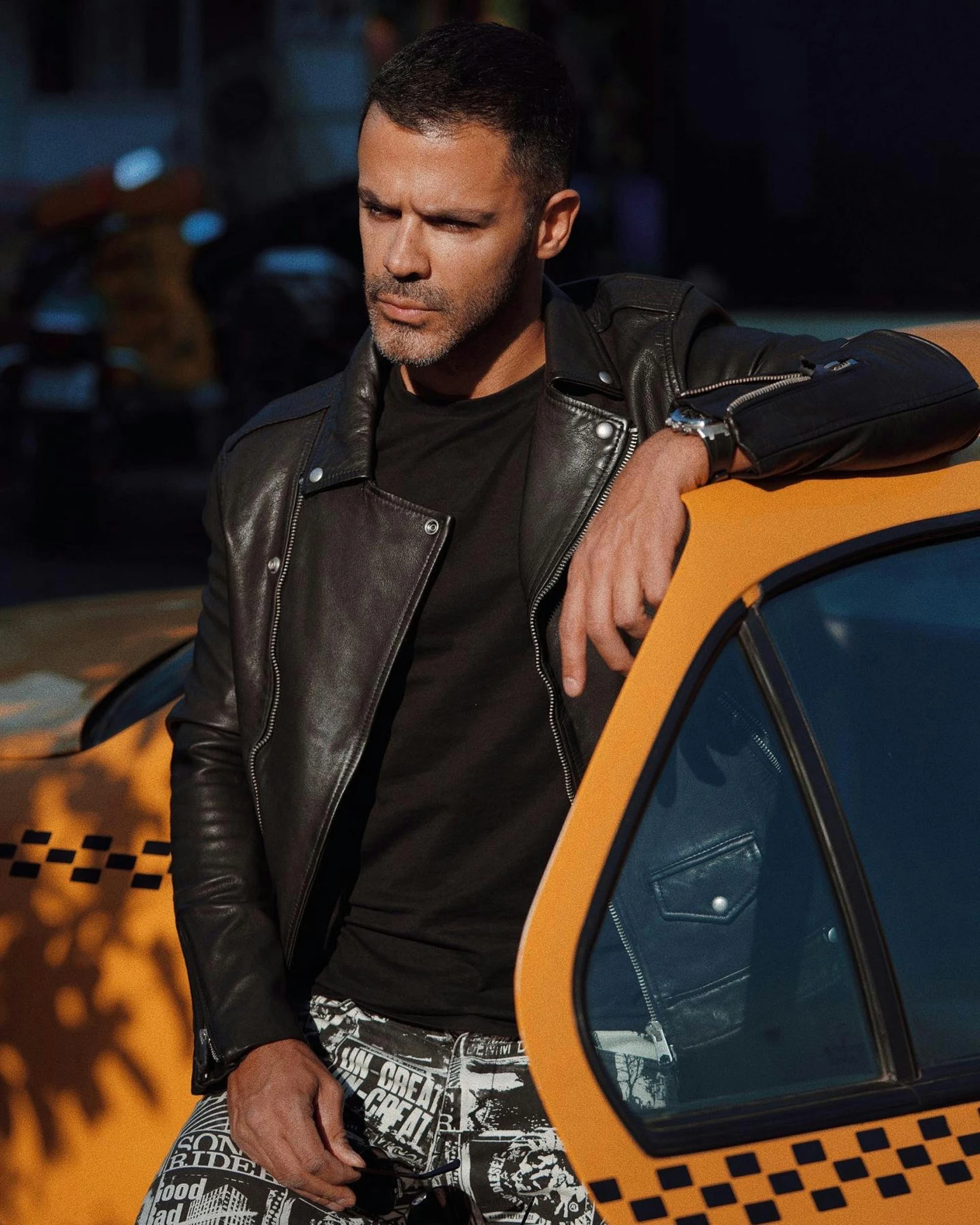 a man in a leather jacket leaning on a taxi, by Adam Saks, instagram model, promo image, watch photo, patterned clothing