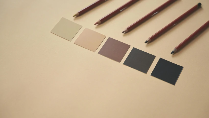 a group of pencils sitting on top of a table, a minimalist painting, inspired by Kyffin Williams, tonalism, squares, matte paint colors, brown colours, product view