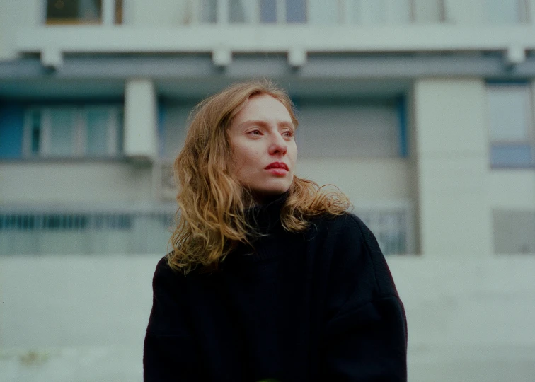 a woman with long hair standing in front of a building, wearing a black sweater, petra collins and mc. escher, elizabeth olsen, portrait image