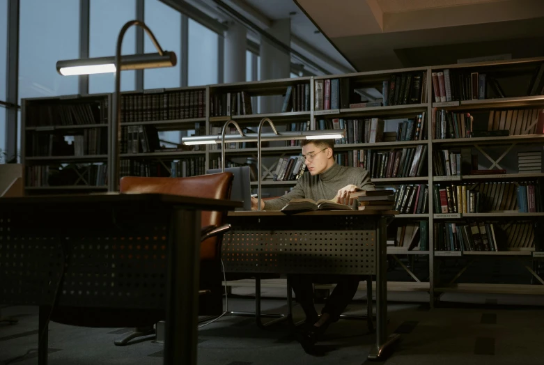 a man sitting at a desk in front of a laptop computer, by Adriaen Hanneman, unsplash, academic art, in a gloomy library, ignant, azamat khairov, light source from the left