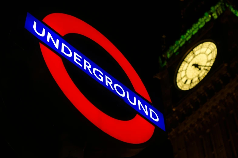 a london underground sign with a clock tower in the background, by Rupert Shephard, shutterstock, it's getting dark, square, tournament, night photo