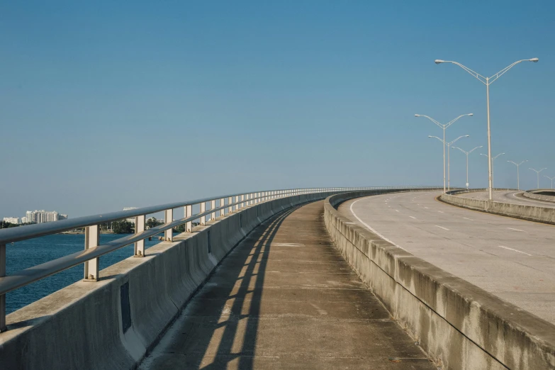 a long bridge over a body of water, by Carey Morris, unsplash contest winner, postminimalism, empty streetscapes, clear blue skies, curving, in louisiana